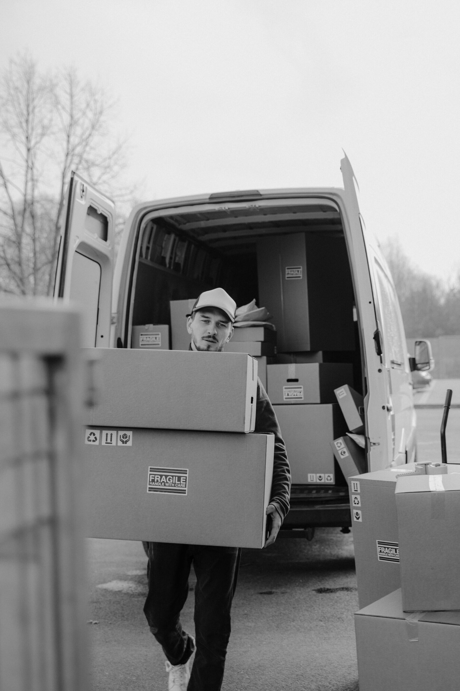 A courier carries cardboard boxes to a delivery van, ready for shipment.